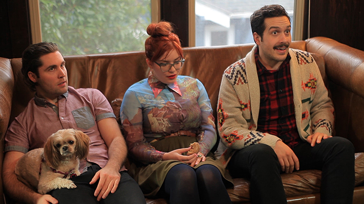 A still from the Finale: Greg, Alice and Rob sitting on a couch with a small dog